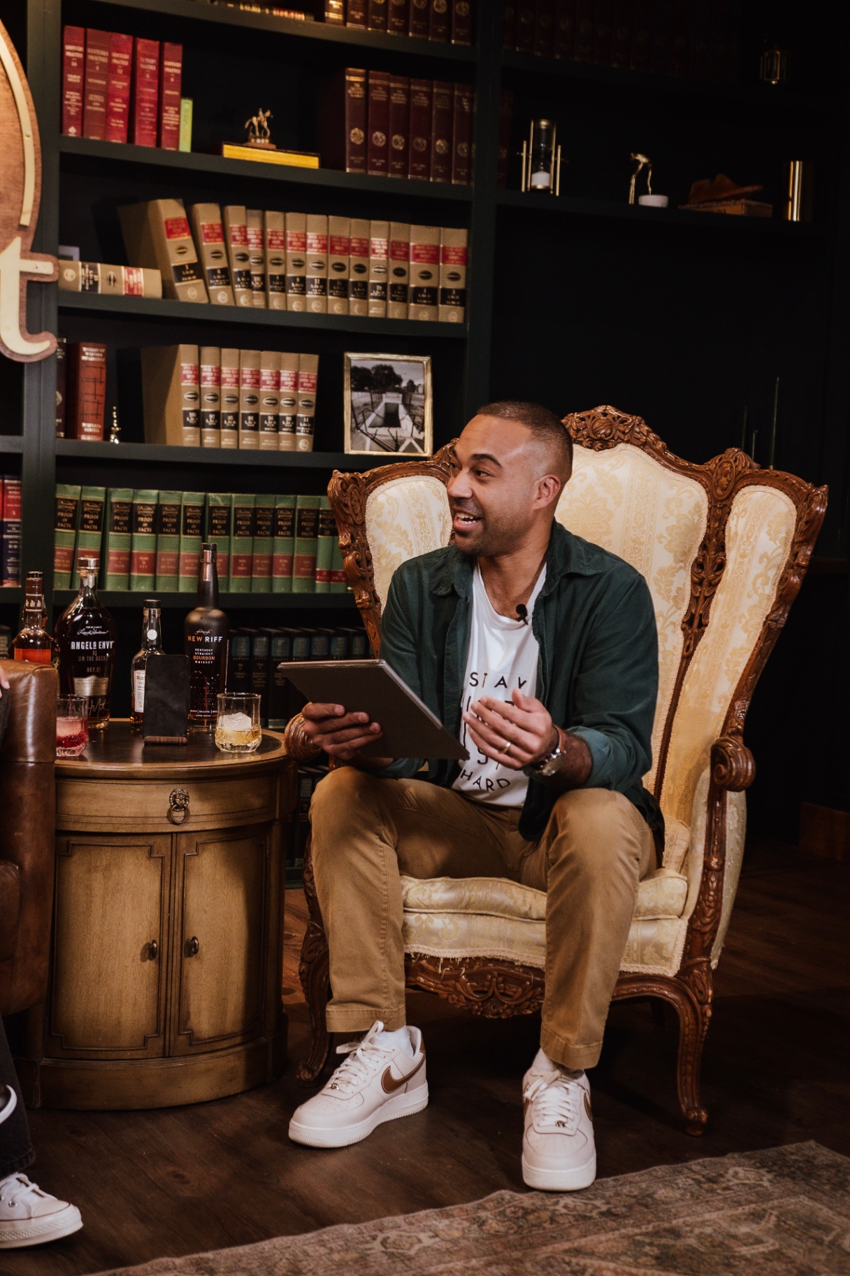 Host Arian Green seated in the carved armchair with a tablet of questions during a taping of AI on the Rocks at The Fort